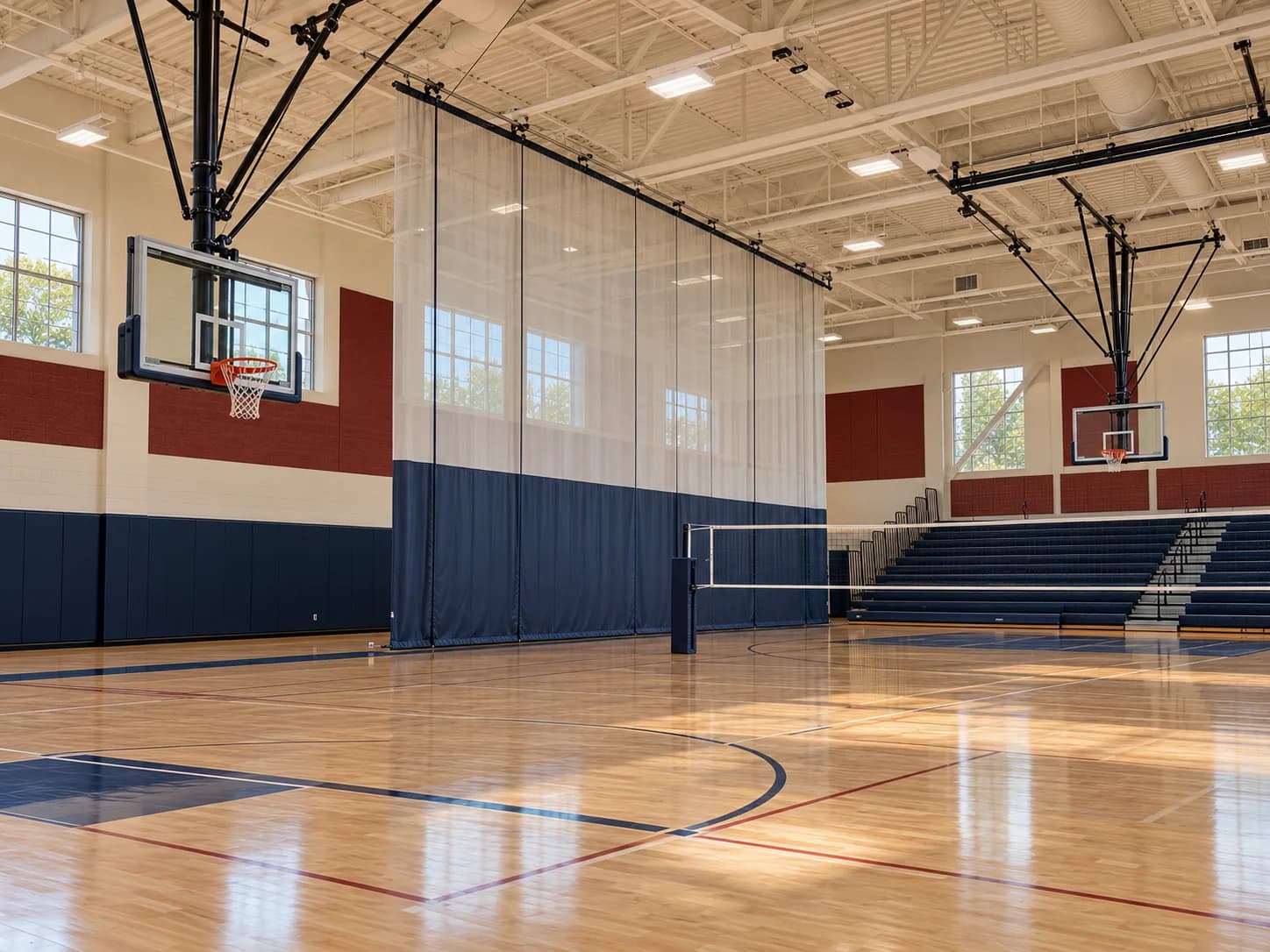 Unbranded gymnasium with basketball backstops, divider curtain, volleyball net, and bleachers